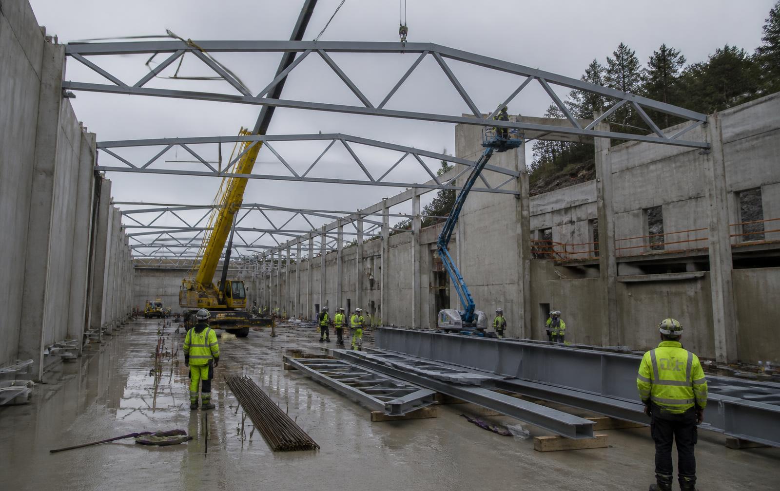 Stor idrettshall under bygging med plasstøypte betongveggar og stålbjelkar under montering